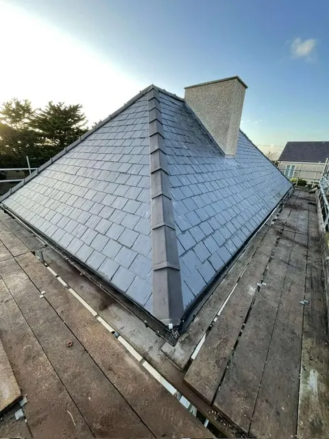 New slate roof meeting a rendered chimney stack, seen from the scaffold. One of our jobs.